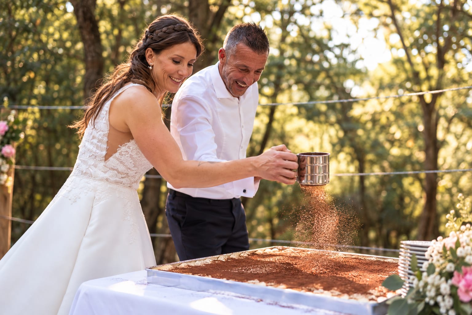 Les mariés saupoudrant ensemble le cacao sur un tiramisu géant en plein air